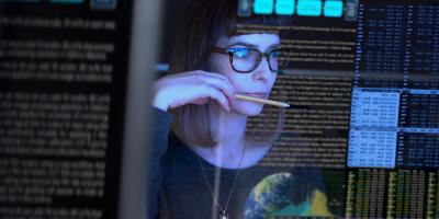 Woman in glasses looking into a computer 