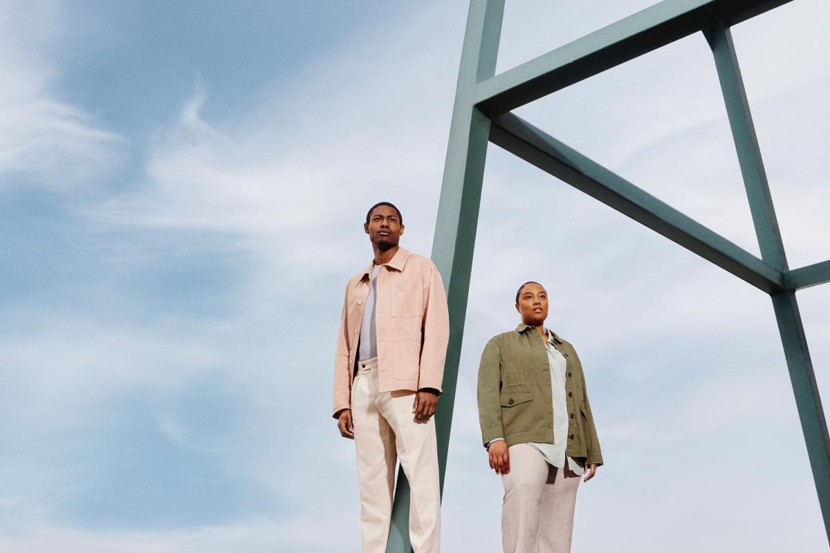 Expansive light blue-sky backdrop, with a man and a woman in the foreground standing next to a metal structure